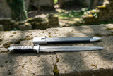 Eastern Dirk in sheath on stone surface, featuring Damascus blade and leather-wrapped grip, showcasing medieval craftsmanship.
