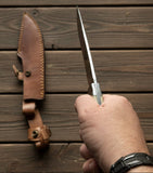 Replica Persian Fighting Knife with Damascus Blade Man At Arms held in hand above leather sheath