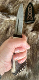 Hand forged sgian dubh with a crown stag handle held in hand, showcasing its Damascus blade and craftsmanship.