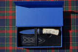 A hand forged Sgian Dubh with carbon steel blade with a hand-carved deer antler handle, presented in a blue display box with a cow leather sheath. 