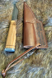 Norse Viking Utility Scramasax Damascus Blade with olive wood handle and leather sheath on fur background.