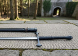 Late Crusader medieval sword displayed on stone surface with forest background and castle entrance.