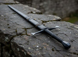 Late Crusader medieval sword resting on a stone wall, featuring a hand forged blade and full tang construction.