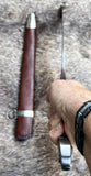 The Bedford Medieval Sword Hilted Dagger being held with its sheath beside it on a textured surface.