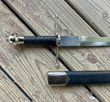 Main Gauche Parrying Dagger lying on wood surface with leather handle and metal accents