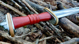 Close-up of the Migration Era Sword handle by Man at Arms, designed by Bruce Brookhart, set among rustic natural materials.