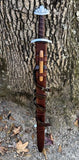 Troll's Bane Viking sword replica displayed against a tree, showcasing the unique design and leather scabbard.
