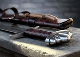 Troll's Bane Viking sword replica displayed with leather scabbard on a stone surface, showcasing intricate details.