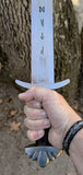 Hand gripping the hilt of the Troll's Bane Viking sword replica showcasing the runes on the blade.