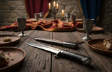 A Renaissance hunting knife with black handle and hand forged blade on a textured surface