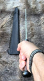 Hand holding The Saxon Langsax or Long Seax with sheath on a fur background.