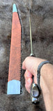 The Saxon Langsax or Long Seax resting on fur background with a hand holding the blade.