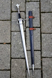 European hand and a half longsword displayed alongside its scabbard on stone paving.