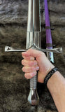 Person holding The Genoa an Italian Bastard Sword with purple grip, showcasing its hand-forged design and detail.